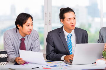 Business meeting in Asia. Image of Asian business partners discussing documents and ideas at meeting.