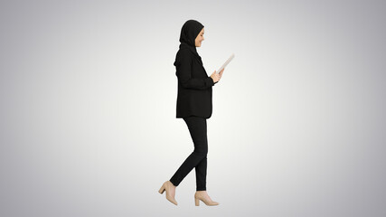 Cute Arabian businesswoman using tablet computer while walking o