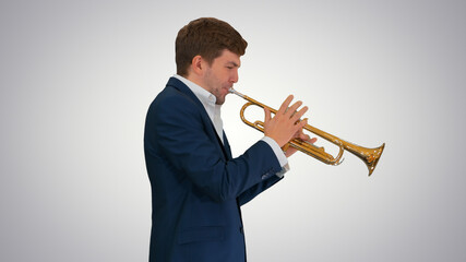 Young man in suit playing a trumpet while walking on gradient ba