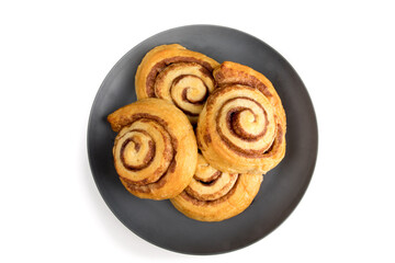 top down view of four fresh baked cinnamon buns on a dark grey plate