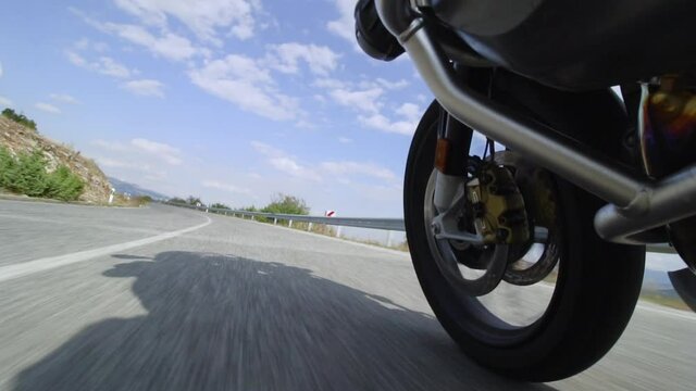 Motorcycle ridind on a road in nature. Close up wheel on a bumpy asphalt road. Recorded at 100 fps.