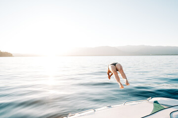 Active young woman diving into a lake at sunset