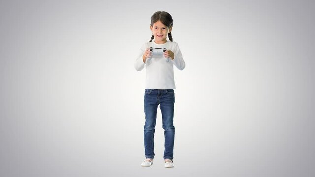 Excited little girl play videogame holding joystick in her hands on gradient background.