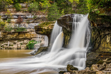 Upper Cataract Falls, a beautiful waterfall in Owen County, Indiana, splashes down in the days of early autumn as leaves are just beginning to change color along Mill Creek.