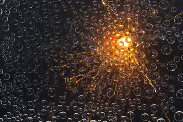Light rays of great outbreak are reflected in transparent water droplets. Black background. Space abstraction. 
