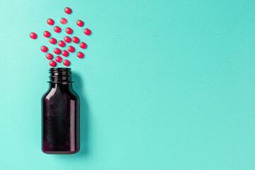 Pills spilling out of bottle  on green background. top view