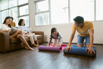 Obraz premium Asian family spending time together in the living room which father and his daughter playing on yoga mat.