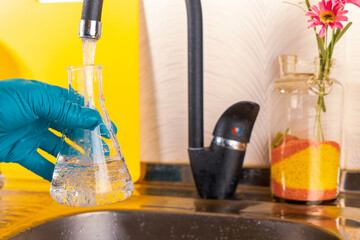 water purification specialist tap water pours into a glass flask.