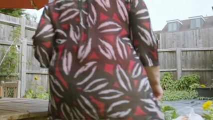Elderly Woman sitting in the garden and opening up her tablet device to speak to friends tapping screen