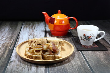 Famous local breakfast menu, Organic grains bread serving with roasted bacon and onion on the wooden plate. Mock up of bread menu in the morning. Selective focus concept.