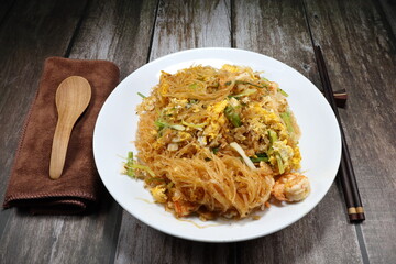 Pad Thai, Fried and stirred vermicelli (Glass noodle) with fresh peeled shrimp, dried shrimp, egg and cutting spring onion on the plate. Famous local street food noodle menu in Thailand.