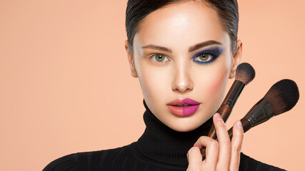 Portrait of a girl with cosmetic brush near face. Woman making makeup on the face using makeup...