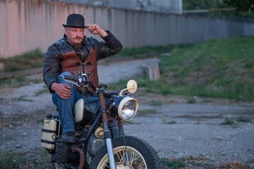 Fototapeta na wymiar brutal biker. beautiful man's mustache. man in a hat. brutal man on a motorcycle