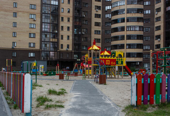 Fototapeta na wymiar children's Playground with a slide, hand crank, stairs on the sand in the middle of residential buildings