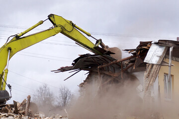       Destruction of the walls of an old building with a crawler excavator bucket.