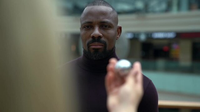 interracial relationship and marriage, black man is looking on white woman with metal ball in hand