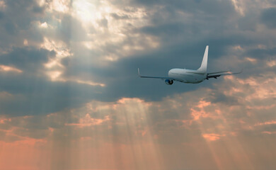Airplane flying over tropical sea at sunset