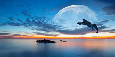 Silhoutte of dolphins jumping up from the sea at sunset with full moon 