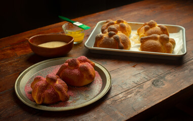 Ingredientes panadería panadero charola pan de muerto mexicano tradicional festividades octubre día de muertos mesa de madera mantequilla rociando azúcar mantequilla colores bonito