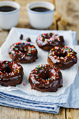 Baked chocolate doughnuts with chocolate glaze and multi color sprinkles