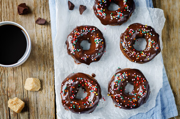 Baked chocolate doughnuts with chocolate glaze and multi color sprinkles