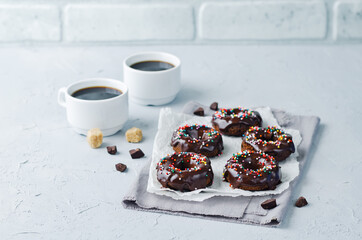 Baked chocolate doughnuts with chocolate glaze and multi color sprinkles