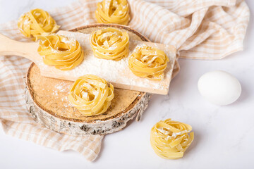 Italian rolled fresh fettuccine pasta with flour on white background.