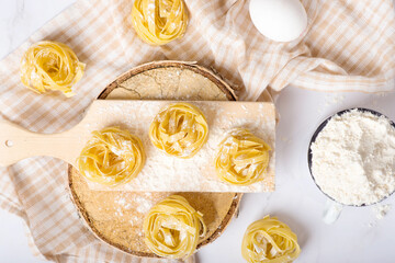 Italian rolled fresh fettuccine pasta with flour on white background.