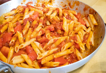 Italian pasta with garlic and oil and diced tomato, pennette rigate pasta, Italian recipe in the pot