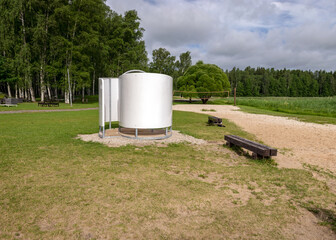 landscape with sandy beach, white dressing room, green grass and wooden benches, summer