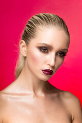 Fototapeta premium Frontal beauty portrait of young woman with perfect makeup over red background.