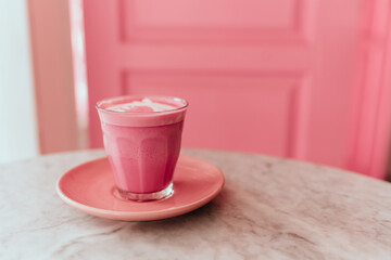 trendy beetroot latte with latte art and flower petals on the foam.