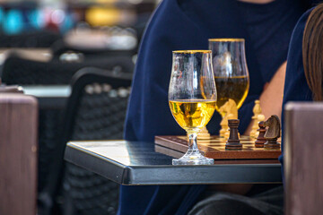 Visitors drink beer and play chess in a street cafe. Rest in a cafe. - Powered by Adobe