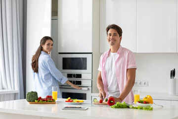 Happy couple is preparing healthy food on light kitchen.