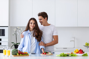 Young happy couple is enjoying and preparing healthy meal in kitchen.