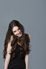 Beautiful woman with long wavy hair posing in the studio on a gray.
