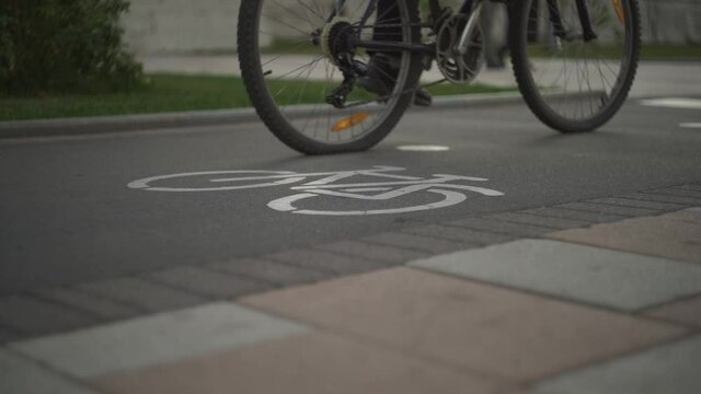Bicycle road sign has been drawn installed on asphalt. Separate bike path in city center. Pedestrian safety. Man rides a bicycle. Food carrier, healthy lifestyle, comfortable movement around the city