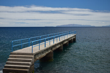 Fototapeta na wymiar A little pier with a blue handrail at the coast of Santa Cruz, Madeira, Portugal.