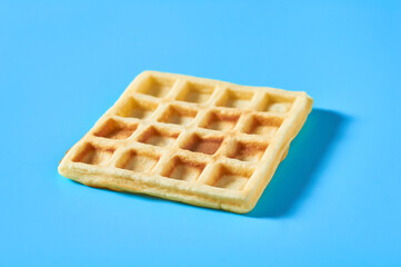 One vanilla belgian waffle on blue background