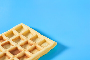 One vanilla belgian waffle on blue background