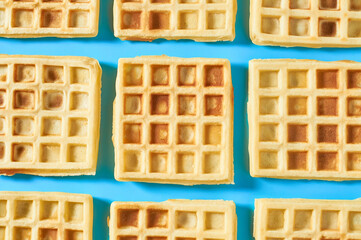 Rows of vanilla belgian waffles on blue background