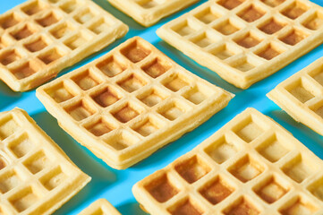 Rows of vanilla belgian waffles on blue background