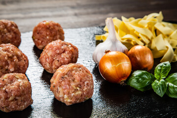 Raw meatballs on black stone board