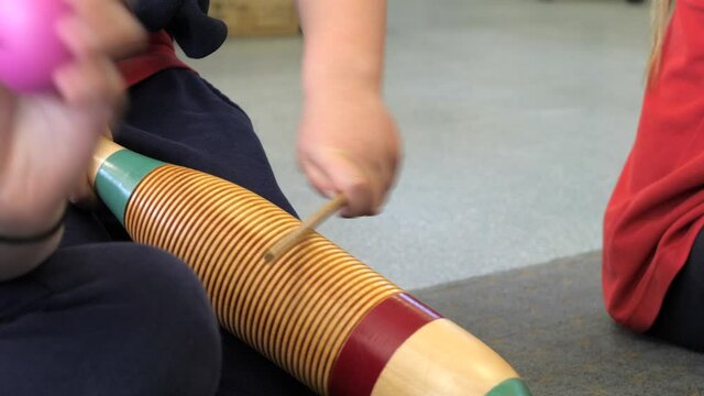 CLOSE UP Child Playing Wood Guiro Percussion Instrument In Music Class