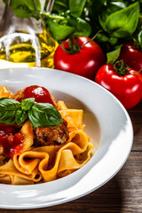Pasta with meatballs in tomato sauce on wooden background
