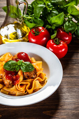 Pasta with meatballs in tomato sauce on wooden background

