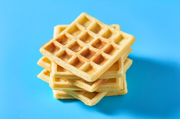 Stack of vanilla belgian waffles on blue background