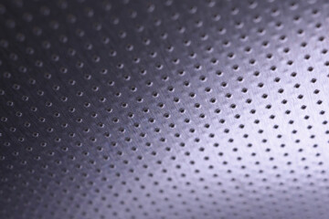 Dark metallic wallpaper. Tinted violet or purple background. Perforated aluminum surface with many holes, hanging from above like a ceiling. Perforation rows go into the distance and form perspective