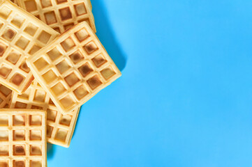 Heap of vanilla belgian waffles on blue background. Top view