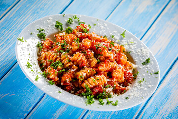 Fusilli with tomato sauce, meat and parmesan on wooden table

